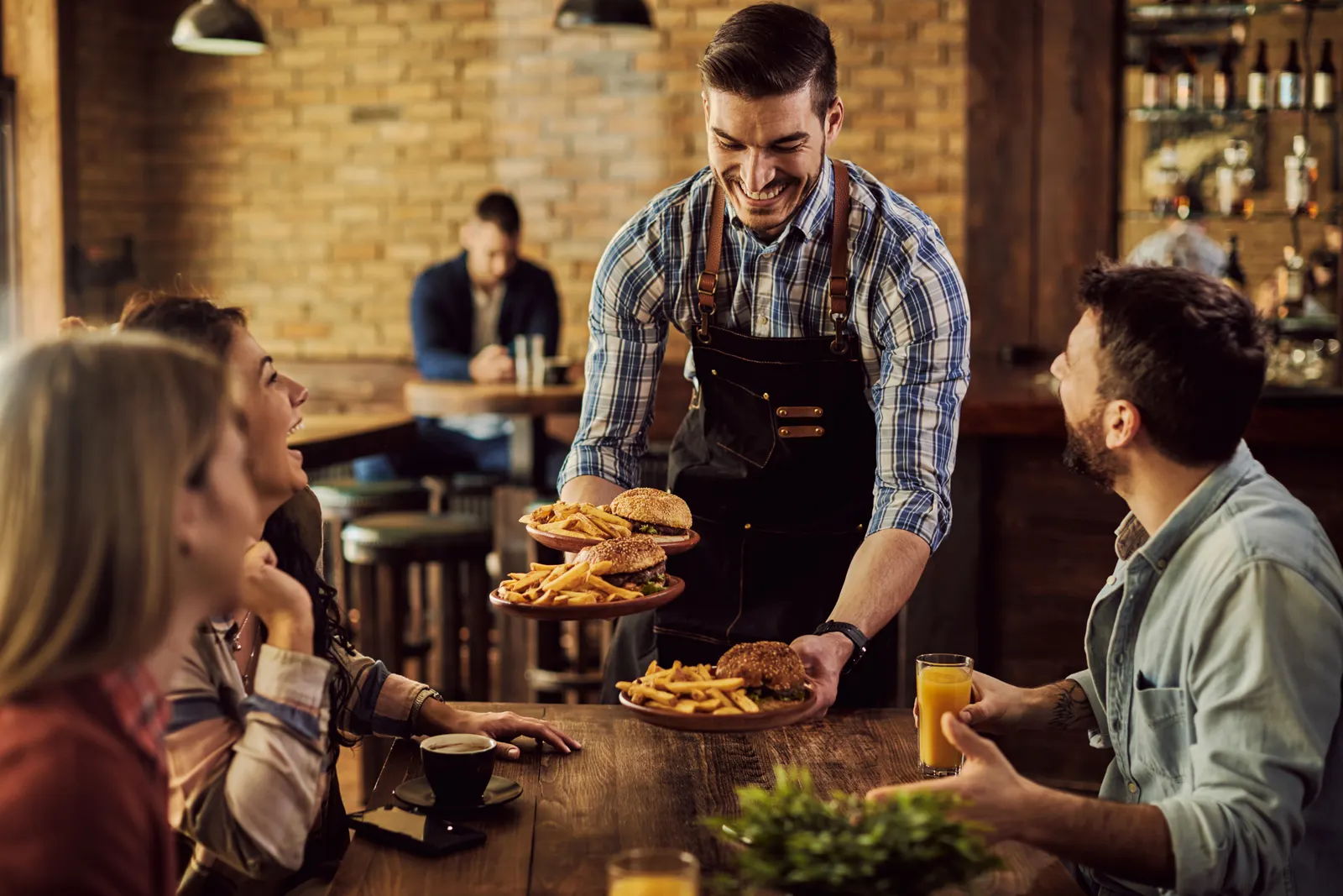 A server bringing plates to a table of friends in a busy restaurant